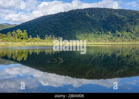 Atemberaubende Spiegelung der von Busch gekleideten Berge an der ruhigen Oberfläche des Lake Moeraki auf der Südinsel Neuseelands. Stockfoto