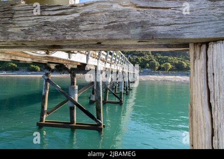 Strukturmuster und Reflexionen unter dem historischen Jackson Bay Pier, Südinsel Neuseeland. Stockfoto