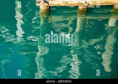 Strukturmuster und Reflexionen unter dem historischen Jackson Bay Pier, Südinsel Neuseeland. Stockfoto