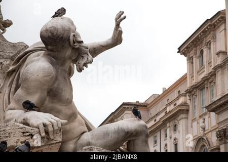 Steinstatue eines Mannes mit seiner Hand dramatisch in der Luft mit Tauben am Körper. Details der Statue Piazza navona Platz, rom, Italien. Stockfoto
