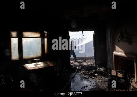 Athen, Griechenland. 4.. Juni 2022. Ein Feuerwehrmann kämpft am 4. Juni 2022 vor einem Haus in Voula, einem südlichen Vorort von Athen, Griechenland, gegen ein Feuer. Am Samstagnachmittag brach im südlichen Küstenabschnitt von Athen ein großes Waldbrand aus, der die Feuerwehr zu einer großen Reaktion veranlasste, als der Brand Wohngebiete erreichte. Quelle: Marios Lolos/Xinhua/Alamy Live News Stockfoto