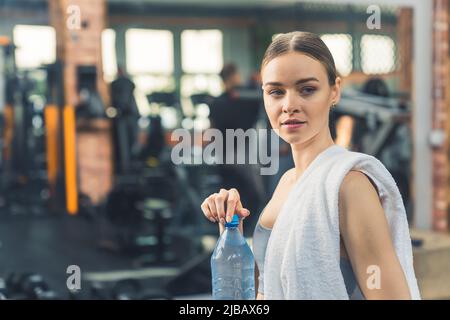 Nahaufnahme Porträt eines kaukasischen tausendjährigen wunderschönen Mädchens, das eine Wasserflasche öffnet und sich nach einem anstrengenden Training entspannt. Hochwertige Fotos Stockfoto