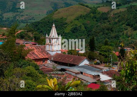 Turm der Kirche der Stadt Ocamonte in kolumbien mit Dächern und Berg im Hintergrund Stockfoto