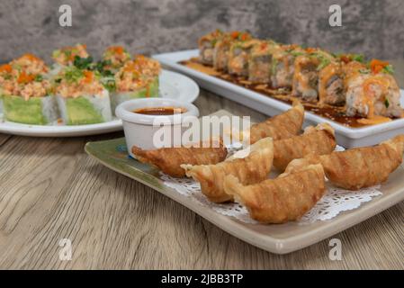 Asiatische Küche Schlemmen Sie auf dem Tisch mit einer Auswahl an Sushi-Brötchen oder frittierten Gyoza zu essen. Stockfoto