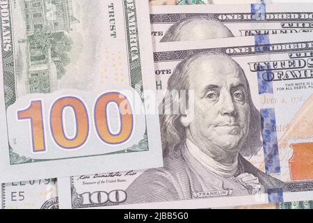 Montage Nahaufnahme des großen 100-Nummern-Designs auf der Rückseite eines USA One Hundred Dollar Bill zusammen mit einer weiteren Notiz, die Benjamin Franklin zeigt. Stockfoto