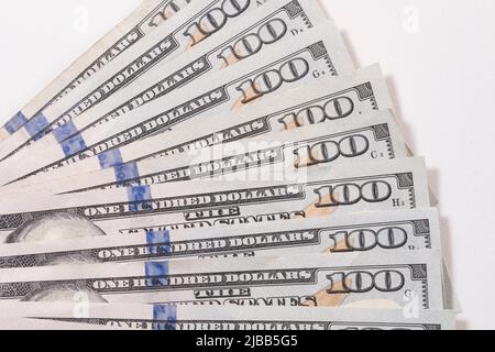 Eine Gruppe von einhundert US-Dollar-Banknoten, die in einem fächerähnlichen Musterstapel auf einem weißen Tisch ausgestellt sind. Stockfoto
