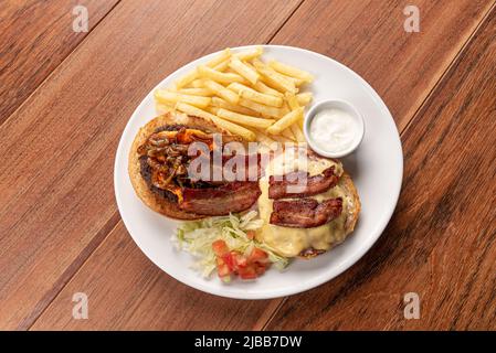 Frischer Burger aus der Nähe auf einem Holztisch mit Pommes Frites. Köstlicher Cheeseburger. Hausgemachter Hamburger mit Rindfleisch, Speck und Käse. Stockfoto