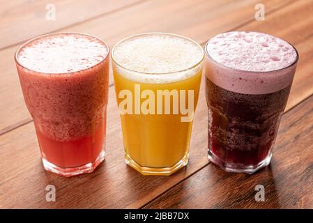 Bunter frische Fruchtsäfte in hohe Gläser auf einem hölzernen Hintergrund serviert. Stockfoto