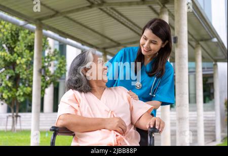 Asiatische sorgfältige Pflegekraft oder Krankenschwester, die sich im Rollstuhl um den Patienten kümmert. Konzept der glücklichen Ruhestand mit der Pflege von einem Betreuer und Ersparnisse und s Stockfoto