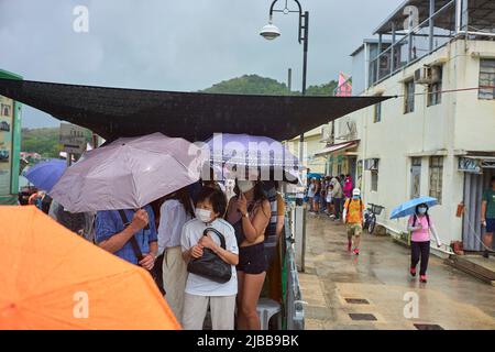 Hongkong, China. 03.. Juni 2022. Die Zuschauer schützen sich vor dem Regen während der Drachenbootrennen im Dorf Tai O. Jedes Jahr, am 5.. Tag des Mondmonats 5., werden Drachenbootrennen in ganz Hongkong organisiert. Kredit: SOPA Images Limited/Alamy Live Nachrichten Stockfoto