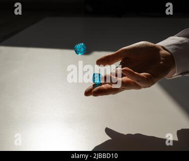 Frau wirft ein Paar blaue transparente Würfel. Stockfoto