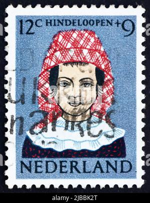 NIEDERLANDE - UM 1960: Eine in den Niederlanden gedruckte Briefmarke zeigt Mädchen in regionalem Kostüm, Hindeloopen, um 1960 Stockfoto