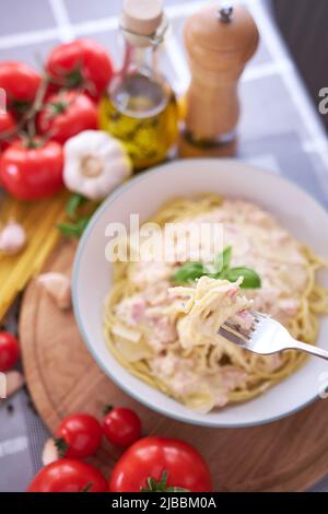 Hausgemachte Pasta Carbonara mit frischem Basilikum und Parmesan in Keramikschale Stockfoto