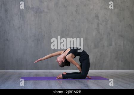 Portrait wunderschöne junge Frau, die drinnen Yoga praktiziert. Schönes kleines Mädchen üben gesunden Lebensstil. Service und Entspannung, weibliches Glück. Horizontaler unscharfer Grunge-Hintergrund Stockfoto