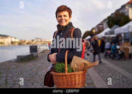 Frau auf dem Bauernmarkt in Prag mit einem Korb mit Gemüse Stockfoto