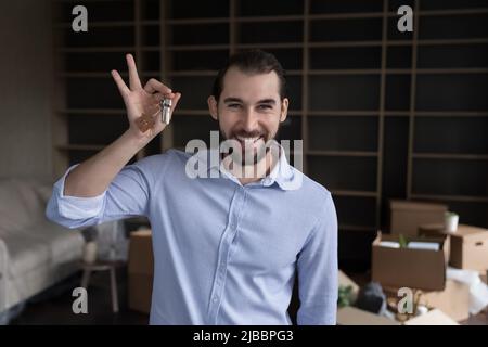 Glücklicher Tausendjähriger Kerl, der einen Haufen Schlüssel vor der Kamera zeigt Stockfoto