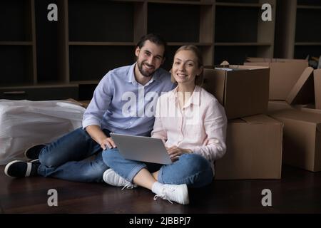 Enthusiastische Millennial Hausbesitzer Paar verwenden Laptop am Umzugstag Stockfoto