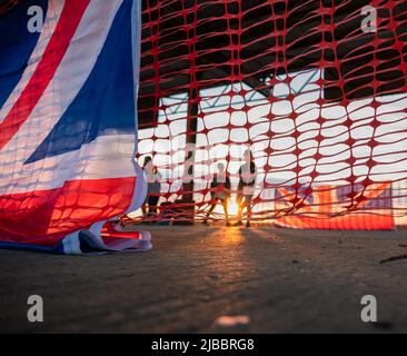 Union Flag und Plastikrollzäune im Sonnenuntergang Stockfoto