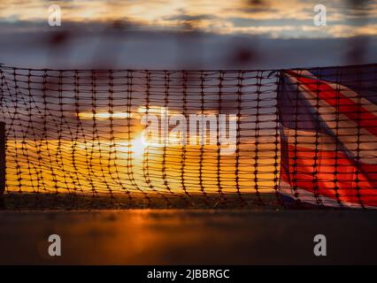 Union Flag und Plastikrollzäune im Sonnenuntergang Stockfoto