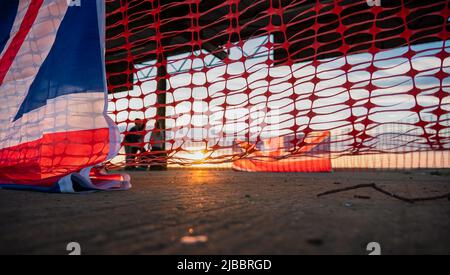 Union Flag und Plastikrollzäune im Sonnenuntergang Stockfoto