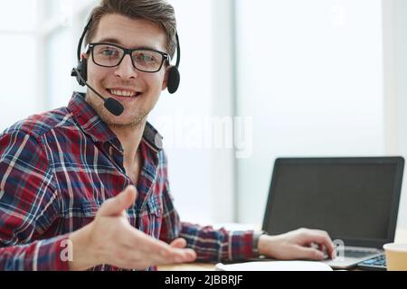 Porträt eines schönen männlichen Kundenservice in Kopfhörern. Callcenter-Mitarbeiter sprechen mit Kopf in einem modernen Büro Stockfoto