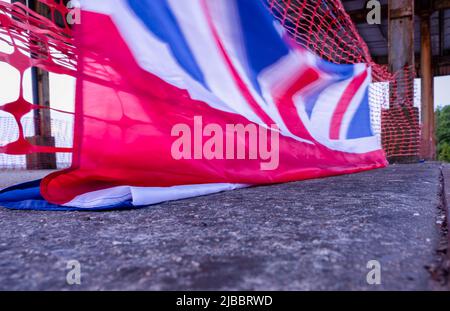 Union Flag und Plastikrollzäune im Sonnenuntergang Stockfoto