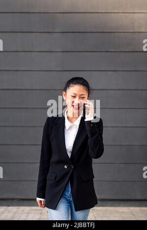 Lächelnde asiatische Geschäftsfrau, die am Telefon spricht Stockfoto