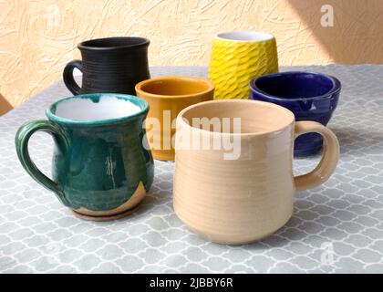 Keramikbecher in verschiedenen Farben und Größen aus nächster Nähe. Mehrfarbige Cups mit speziellen glasierten bedeckt. Keramikgeschirr mit glänzender Oberfläche. Keramik pro Stockfoto