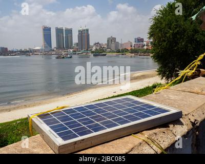 Dar es Salaam, Tansania - Februar 2021: Stadtzentrum mit Wolkenkratzern vom Fährterminal Kigamboni aus gesehen, und einer Solarbatterie auf dem ersten Plan Stockfoto