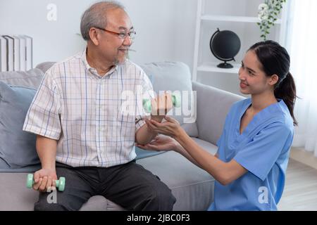 Eine junge Unterstützung, die einem älteren Mann beim Arbeiten hilft. Eine Krankenschwester kümmert sich während der Übung um ältere Patienten. Stockfoto