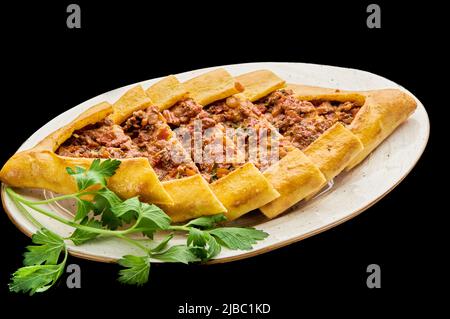 türkische Pizza Pide mit Huhn liegt auf einem Teller auf einem schwarzen isolierten Hintergrund Stockfoto