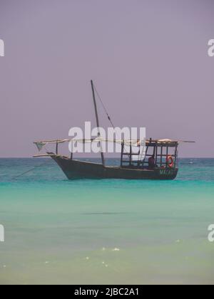 Sansibar, Tansania - Jan, 2021: Traditionelles Dhow-Boot mit gefaltetem Segel im blauen Wasser des Indischen Ozeans vor der Küste von Muyuni, Afrika Stockfoto