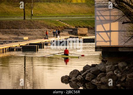 Zagreb, Kroatien-1.. April 2022: Mann im Kajak beim Rudern am see jarun, Kroatien, mit neuen Docks, die vor kurzem am Ufer gebaut wurden Stockfoto