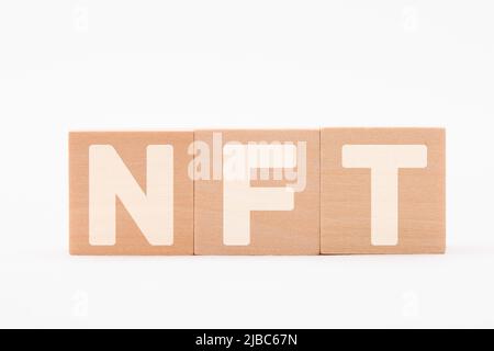 NFT, nicht-fungibler Token-Charakter. NFT-Buchstaben auf einem Holzblock gezeichnet. Weißer Text Stockfoto