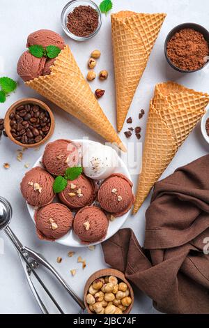 Kugeln aus Schokolade und Speiseeis auf grauem Hintergrund. Stockfoto