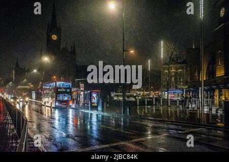 Kings Cross Bahnhof und Bus auf der Euston Road, London, nachts bei starkem Regen. Stockfoto