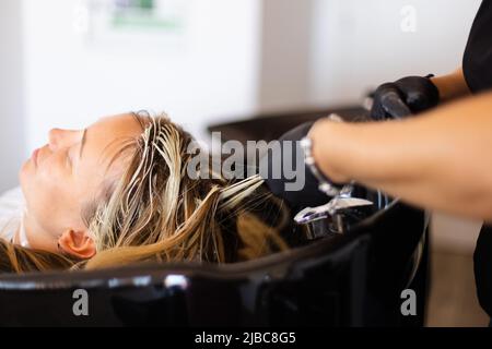 Friseur Nehmen Sie die Folie mit Haarfärbemittel aus den Haaren des Kunden. Stockfoto