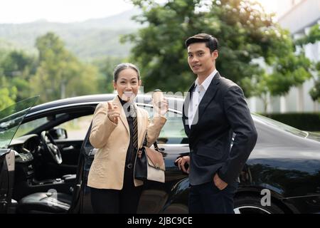 Glückliche alte asiatische Geschäftsfrau und junger asiatischer männlicher Kollege auf dem Parkplatz Stockfoto