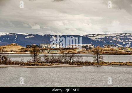 Skutustadir, Island, 29. April 2022: Blick über den teilweise eisbedeckten See Myvatn in Richtung Dorf, hauptsächlich bestehend aus Hotels und Bauernhöfen Stockfoto