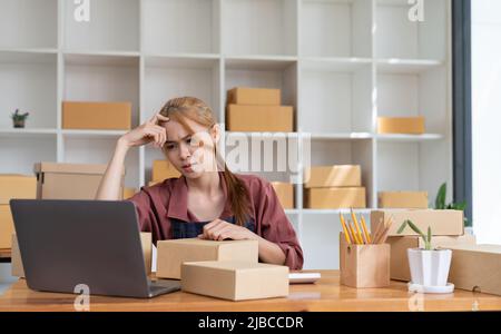 Asiatische Frau denken hart arbeiten Laptop-Computer zu Hause verkaufen online Start-up-Kleinunternehmen Eigentümer, E-Commerce-Ideen-Konzept. Stockfoto