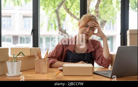 Asiatische Frau denken hart arbeiten Laptop-Computer zu Hause verkaufen online Start-up-Kleinunternehmen Eigentümer, E-Commerce-Ideen-Konzept. Stockfoto