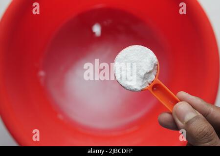 Waschpulver im Plastiklöffel Draufsicht Stockfoto