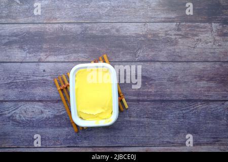 Frische Butter in einem Behälter auf Holztisch Draufsicht Stockfoto