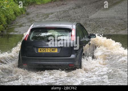 Hall Green, Birmingham, England, 5. Juni 2022. Die Fahrer überqueren eine überflutete Straße in Hall Green, Birmingham, nach starkem Regen über Nacht. Das nasse Wetter hat dazu geführt, dass viele Platin Jubilee Big Lunches in der Gegend abgesagt wurden. Quelle: Stop Press MediaAlamy Live News Stockfoto