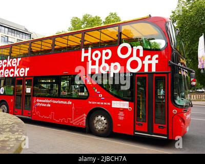 Rote Doppeldecker-Stadtrundfahrt 'Hop on / Hop off'-Bus, der an einer Haltestelle in der Königsallee in Düsseldorf/Deutschland wartet. Stockfoto