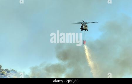 Athen, Griechenland, 4. Juni 2022: Ein Hubschrauber der Boeing CH-47D Chinook wird in einem Waldfeuer auf dem Hymettus-Berg in der Nähe des Vororts Glyfada in Athen eingesetzt. Stockfoto