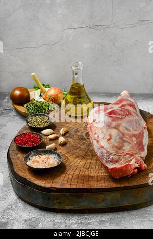 Rohes Lammkeule mit Zutaten zum Kochen auf Holzstumpf Stockfoto