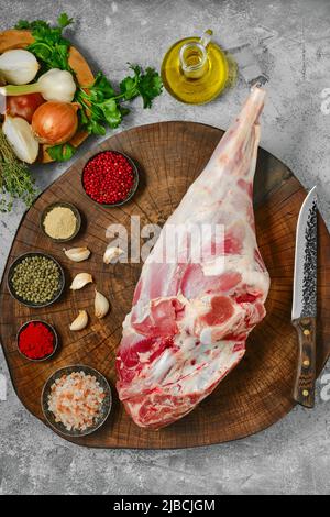 Rohes, ganzes Lammbein-Chump mit Zutaten auf Holzstumpf, Draufsicht Stockfoto