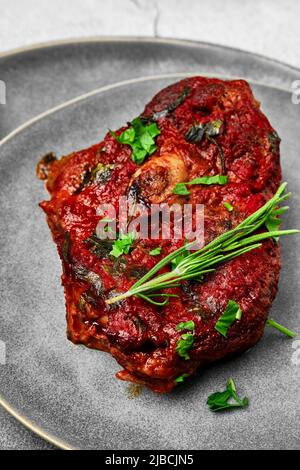 Nahaufnahme von Ossobuco auf einem Teller. Ein Stück Schaft mit Weinsauce gebacken. Stockfoto