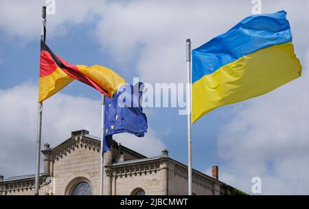 Die Flagge der Ukraine winkt im Wind, während die deutsche Flagge und die Flaggen verwickelt sind Stockfoto